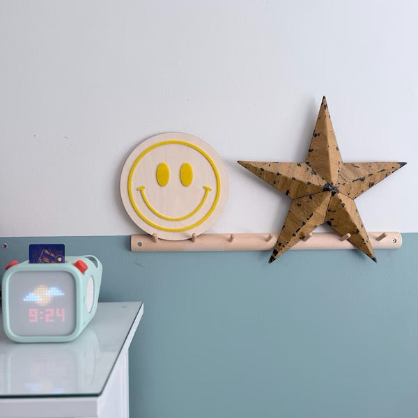 Decorative items including a smiley face wall art, star-shaped object, and digital clock on a shelf.