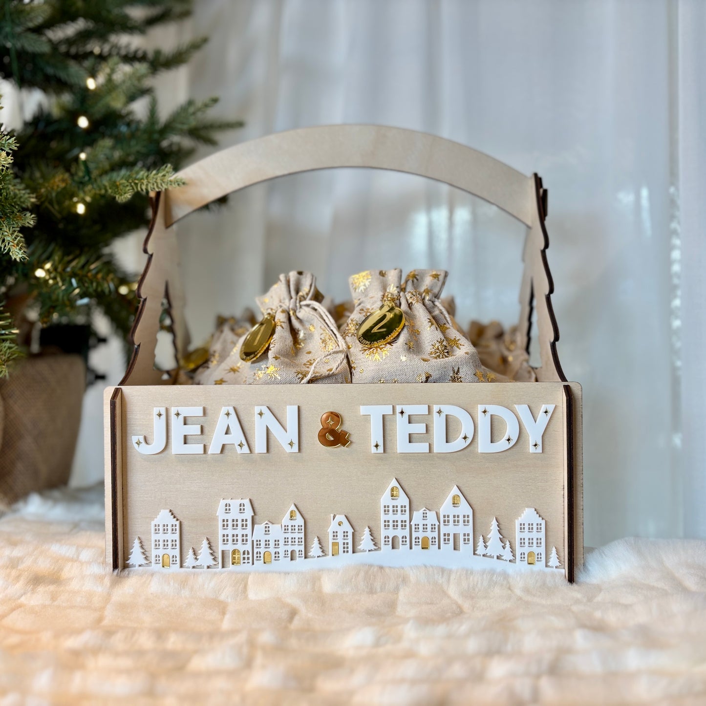 Decorative box with 'Jean & Teddy' text and small bags inside, against a Christmas tree background.