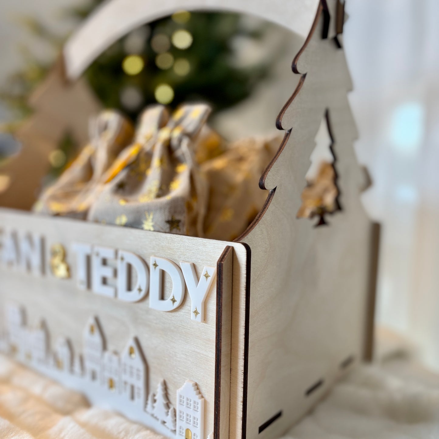 Wooden advent calendar with 'Santa Teddy' text, Christmas tree design, and blurred festive background.